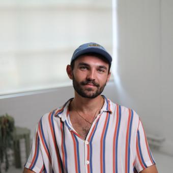 Earth Minutes speaker, Elliot Arthur-Worsop, sat in chair in red, white and blue stripe shirt and blue cap